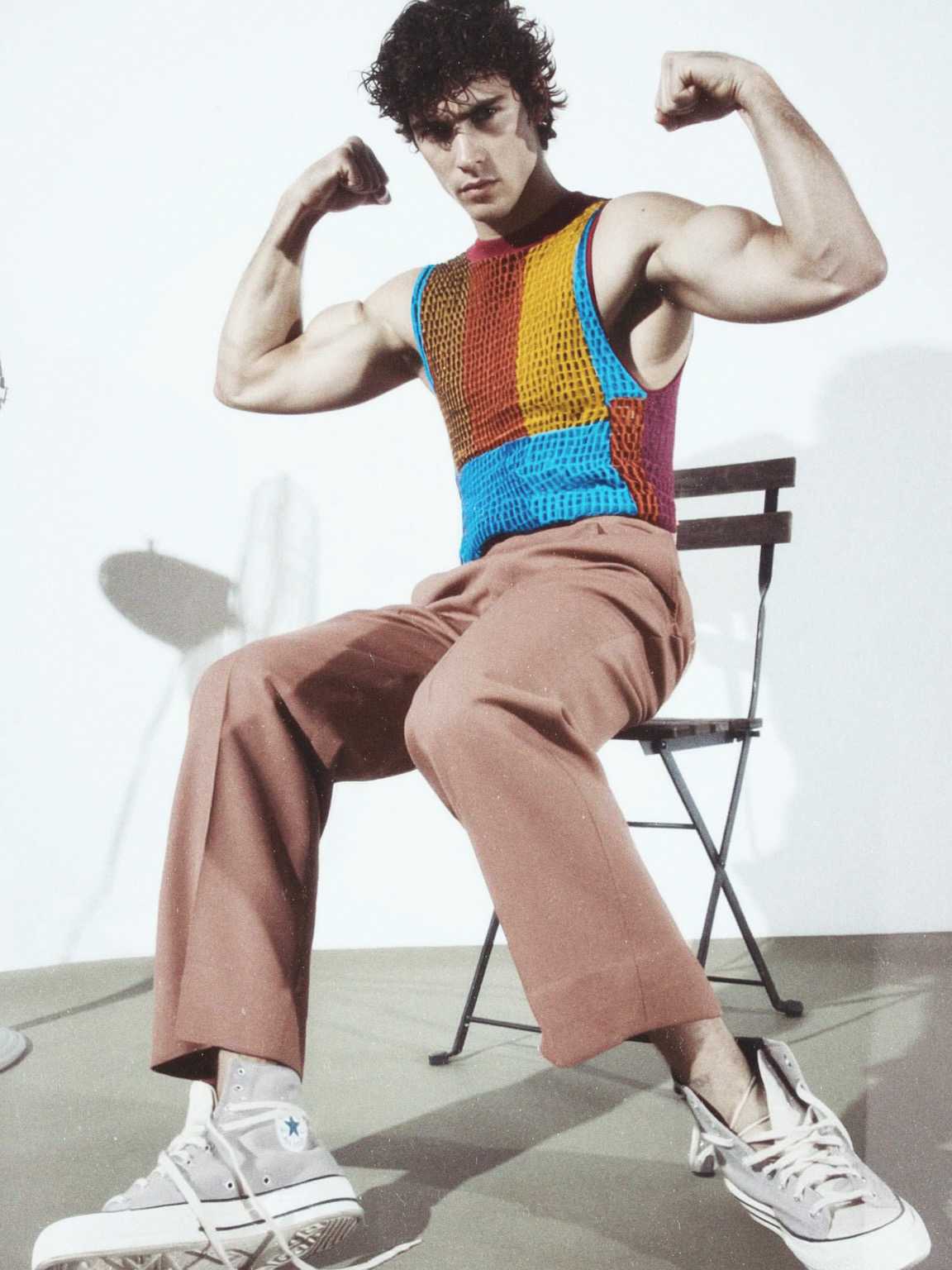 long-lens candid of Damon Cael passing by storefront lights, rising pop artist Damon Cael.